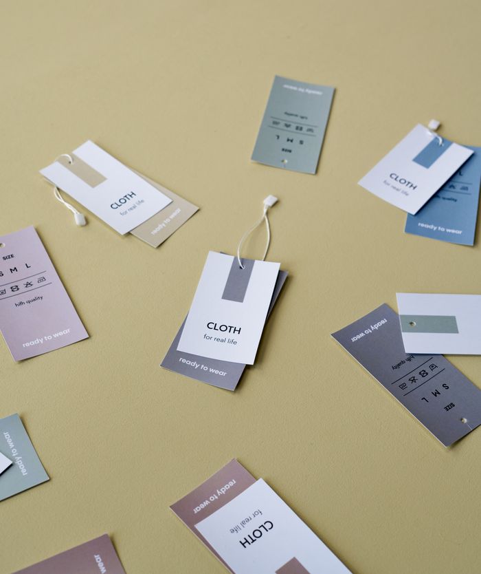 A flat lay of assorted clothing tags on a minimal yellow background, ideal for fashion and retail concepts.